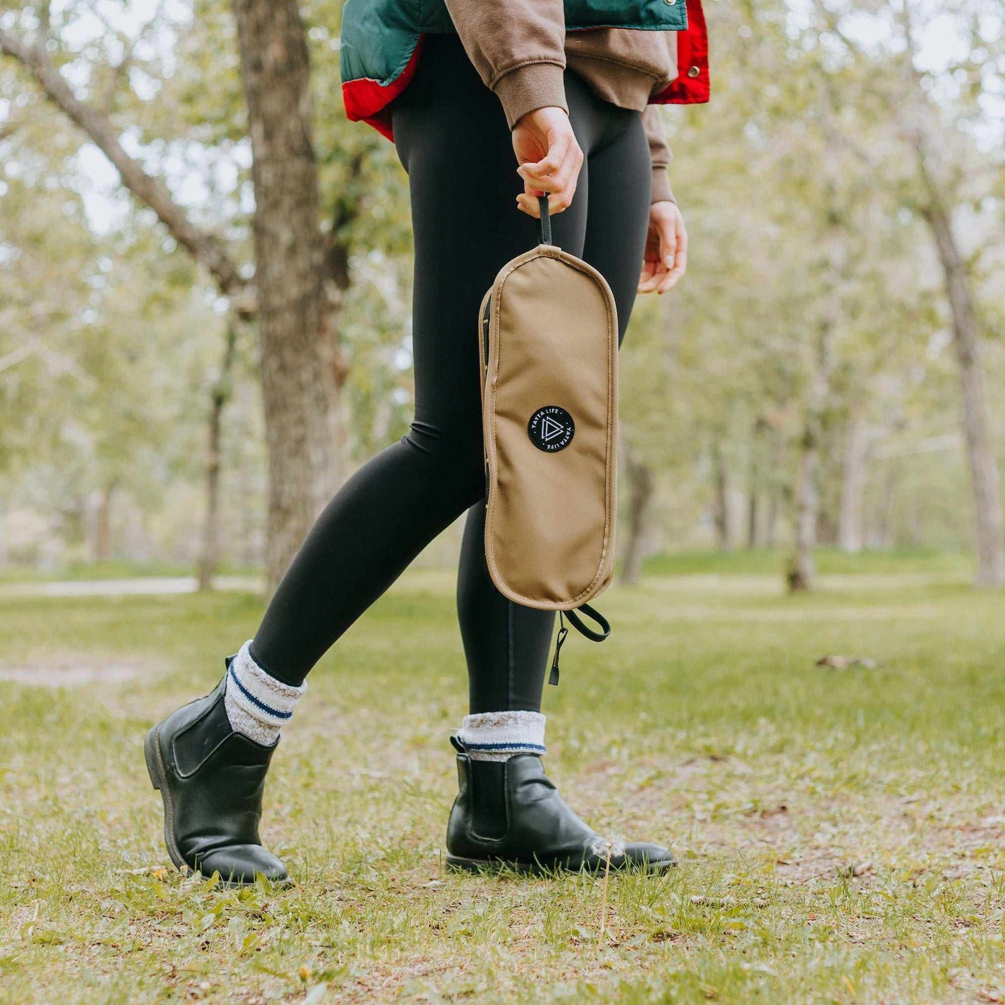Grey Erebus portable camping seat compactly carried by a person in a park setting