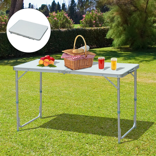 Taupe Shadow foldable camping table set up outdoors with picnic basket and beverages