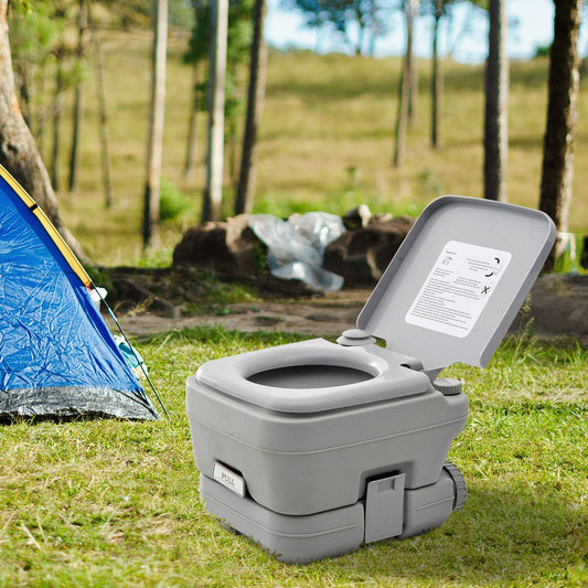 Portable camping toilet with flush next to a tent in a natural outdoor setting